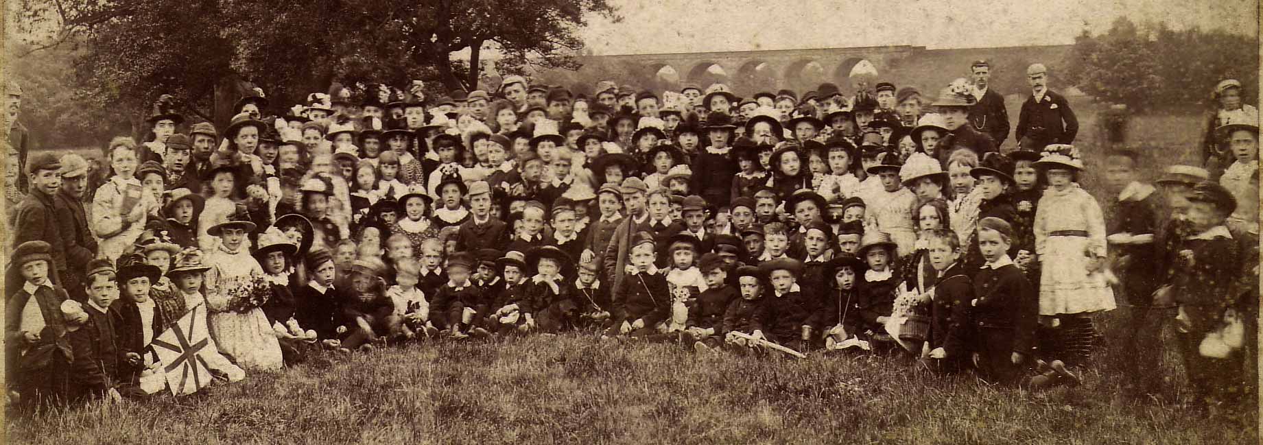 Zoom-in to a cabinet print by James Pike showing a group of children with a viaduct in the background