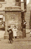 Zoom-in to the old well in front of John Knox House in the Royla Mile, Edinburgh  - Detail from a Postcard by W J Hay in the 'Knox Series'