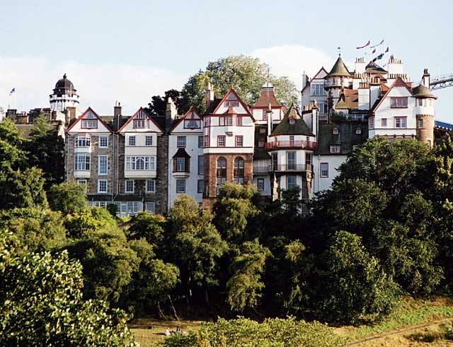 Ramsay Garden as seen from Princes Street with the flags of the Edinburgh Militray Tattoo on the Castle Esplanade in the background.