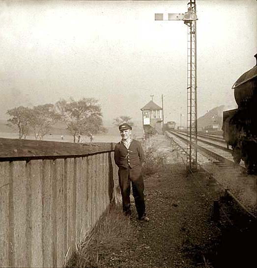 A railwayman stands beside the track as an engine passes heading towards a signalbox. Where is it?
