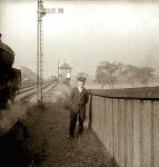 A railway worker stands beside the track as a train passes heading towards a signalbox.  Where is it?