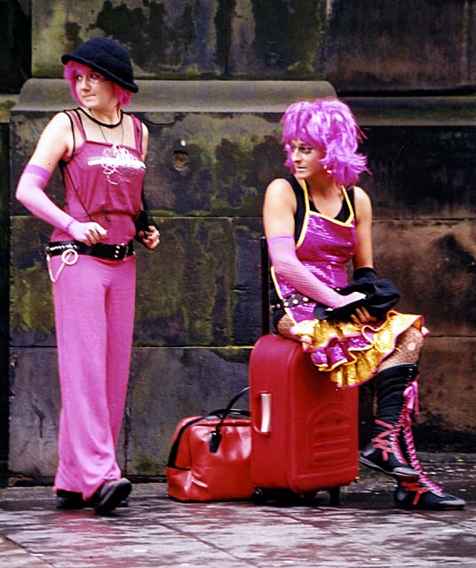 Two visitors to the Royal Mile, dressed in pink, wait for their turn to perform.