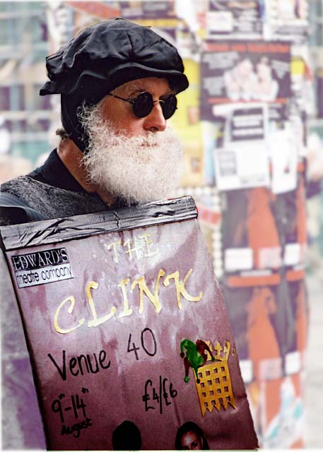 A man, with a poster advertising one of the Edinburgh Fringe shows, stands in the Royal Mile