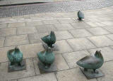 A flock of pigeons in bronze on the pavement at Elm Row