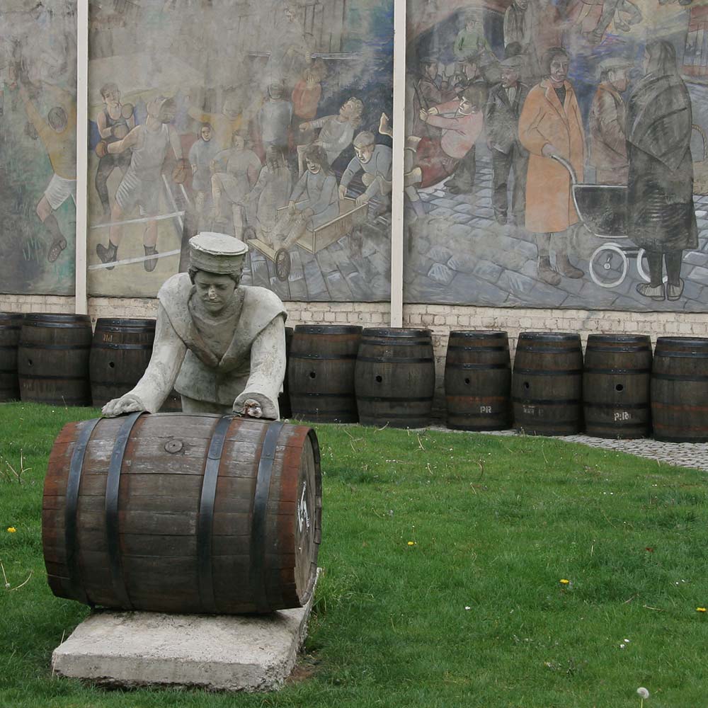 A Sailor rolls out a Barrel, in front of a mural on a gable end at North Junction Street, Leith, depicting Leith's historic connections with the sea