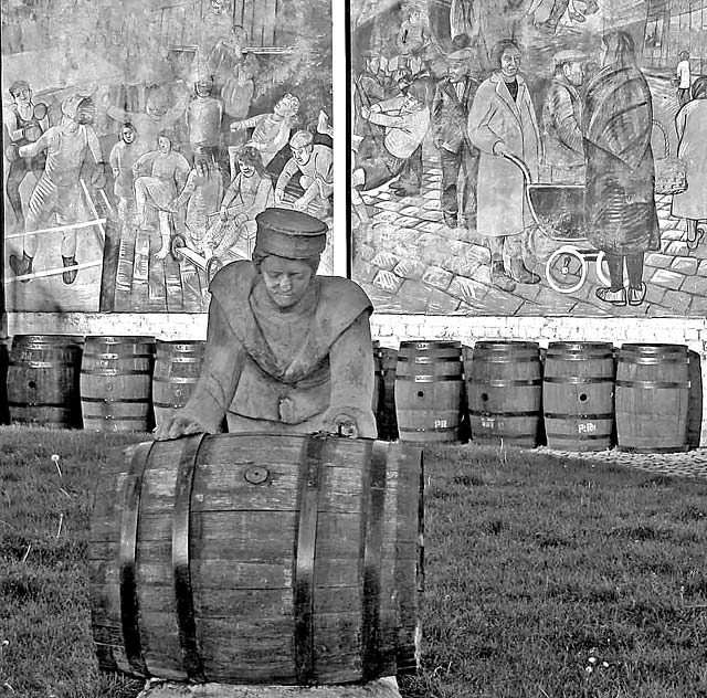 A Sailor rolls out a Barrel, in front of a mural on a gable end at North Junction Street, Leith, depicting Leith's historic connections with the sea