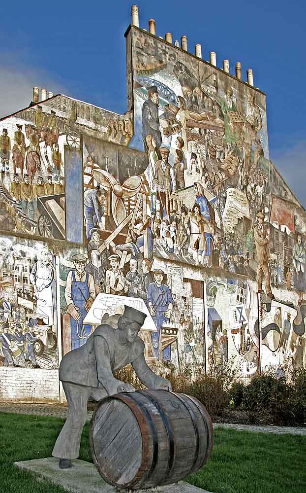 A Sailor rolls out a Barrel, in front of a mural on a gable end at North Junction Street, Leith, depicting Leith's historic connections with the sea