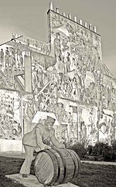 A Sailor rolls out a Barrel, in front of a mural on a gable end at North Junction Street, Leith, depicting Leith's historic connections with the sea