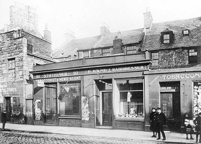 Where and when was this photograph of a row of shops, including E Kane, Hairdresser, taken?