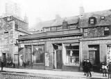 Where and when was this photograph of a row of shops, including E Kane, Hairdresser, taken?